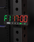 Compact Fortex gym timer attached to a weight rack for interval training tracking.